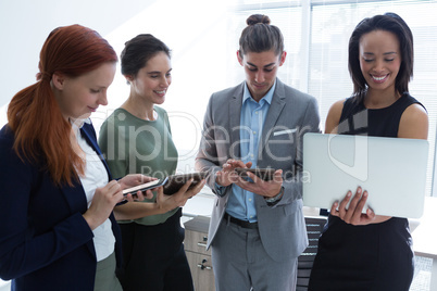 Executives using mobile phone, laptop and digital tablet in the office