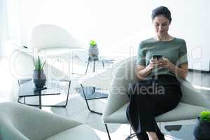 Female executive using mobile phone on chair
