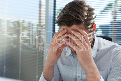 Frustrated executive sitting near the window with hand on head