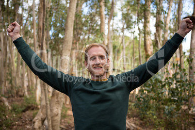 Male hiker standing with the his hands raised in the forest