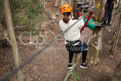 Hiker woman going down a zip line in the forest