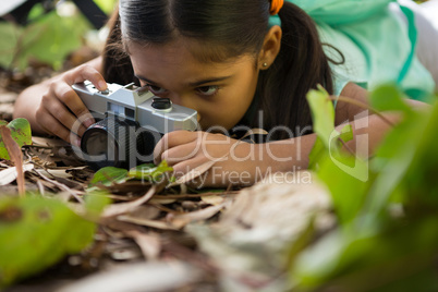 Little girl with backpack lying on floor taking a photo from her camera