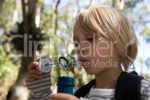 Little girl blowing bubbles on a sunny day in the forest