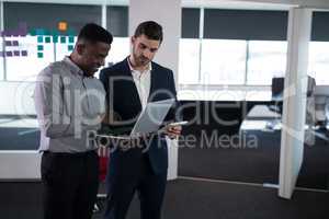 Happy male executives using laptop and digital tablet