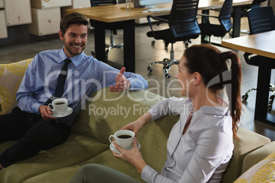 Executive sitting on sofa and having coffee