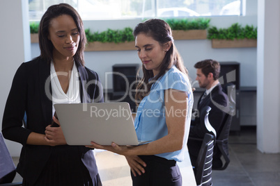 Female executives discussing over laptop