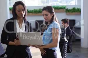Female executives discussing over laptop