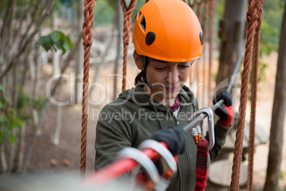 Young smiling woman holding zip line cable in the forest