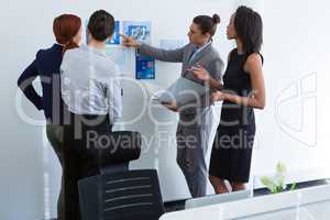 Group of executives discussing over chart on the wall