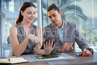 Business executives discussing over digital tablet at desk