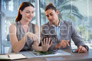Business executives discussing over digital tablet at desk
