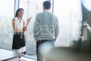 Male and female executives interacting with each other near window