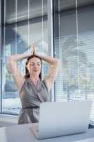 Female executive performing yoga at desk