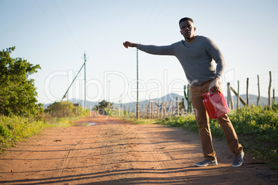 Man with petrol can hitchhiking at countryside