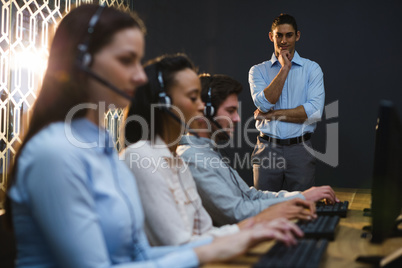 Business executives with headsets using computers at desk