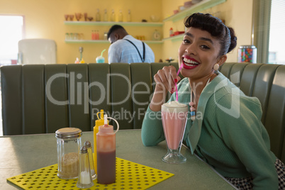 Woman having milkshake at restaurant