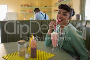 Woman having milkshake at restaurant