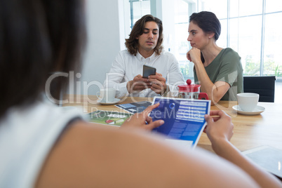 Group of colleague discussing over mobile phone