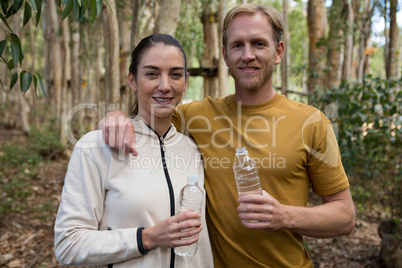 Hiker couple standing in the forest together holding water bottles
