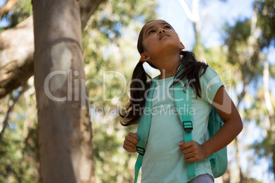 Little girl standing with backpack looking up in the sky