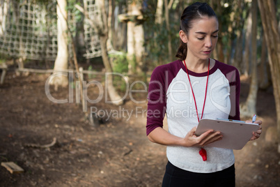 Woman standing in forest holding writing pad