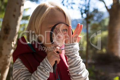 Smiling girl looking at a hand through a magnifying glass
