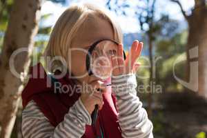 Smiling girl looking at a hand through a magnifying glass