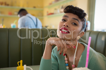 Young woman putting her chin on fist looking into camera at restaurant