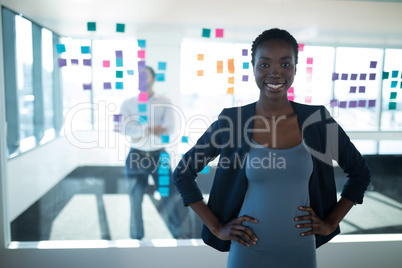 Female executive standing with hands on hip in office