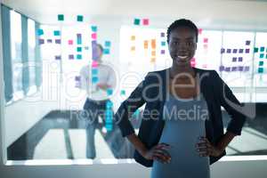 Female executive standing with hands on hip in office