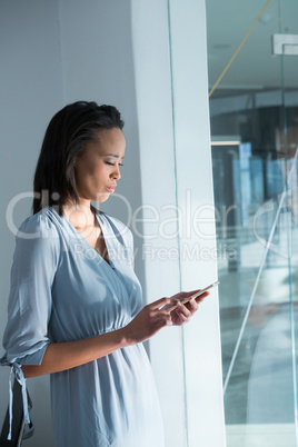 Female executives standing with mobile phone near window