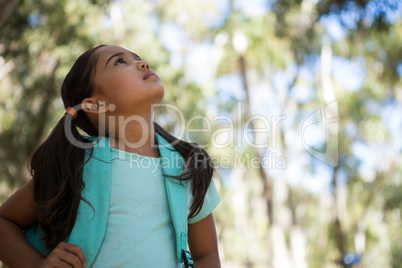 Little girl standing with backpack looking up in the sky