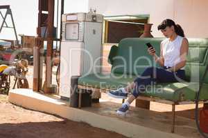 Woman using mobile phone at petrol pump station