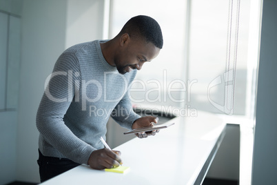Male executive writing on sticky note