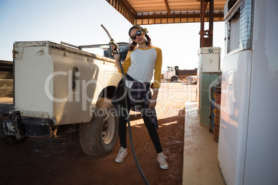 Woman holding a nozzle at petrol pump station