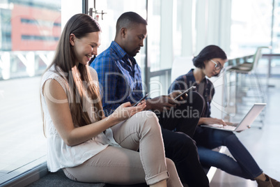 Male and female executives using electronic gadgets