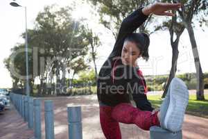 Fit woman stretching her leg on bollard