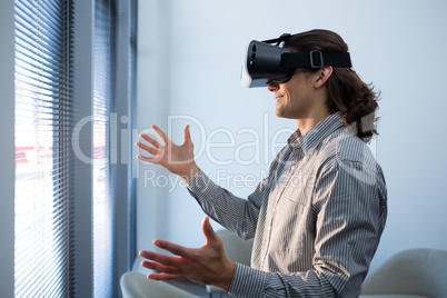 Male executive using virtual reality headset in waiting area