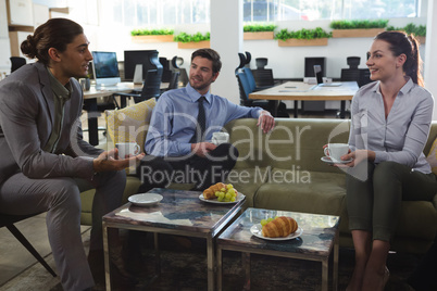 Group of executives discussing while having coffee and snack