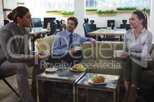 Group of executives discussing while having coffee and snack