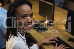 Female executive with headset using computer at desk