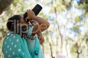 Little girl with backpack taking photos from dslr camera on a sunny day