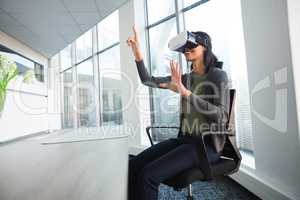 Female executive using virtual reality headset at desk