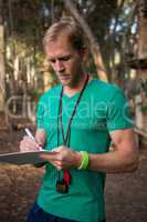 Trainer holding notepad in his hands in the forest on a sunny day