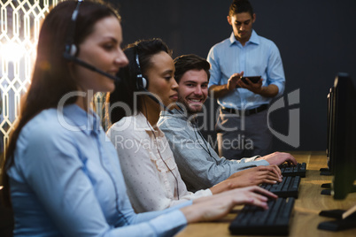 Business executives with headsets using computers at desk