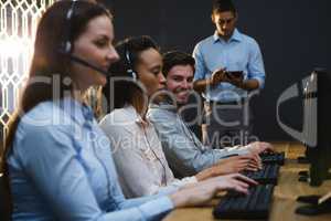 Business executives with headsets using computers at desk