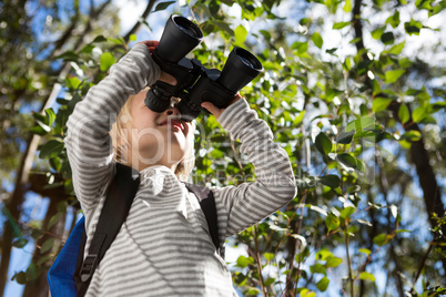 Little girl with bag pack enjoying nature with binoculars