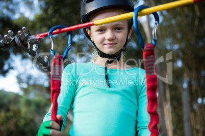 Little girl wearing helmet standing near zip line