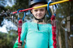 Little girl wearing helmet standing near zip line
