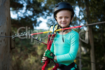Little girl wearing helmet standing near zip line